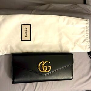 Gucci black clutch with gold Gucci logo.